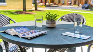 A round table with two chairs, a magazine, two glasses of water, and a potted plant. - Family-Friendly Oasis near Disney and Theme Parks (Kissimmee)