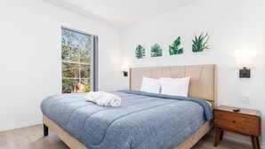 A bedroom with a bed, a nightstand, a window, and wall art. - Family-Friendly Oasis near Disney and Theme Parks (Kissimmee)