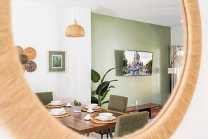 Ein Essbereich mit einem Holztisch, gedeckt für vier Personen, einer großen grünen Wand und einem gerahmten Bild darüber.