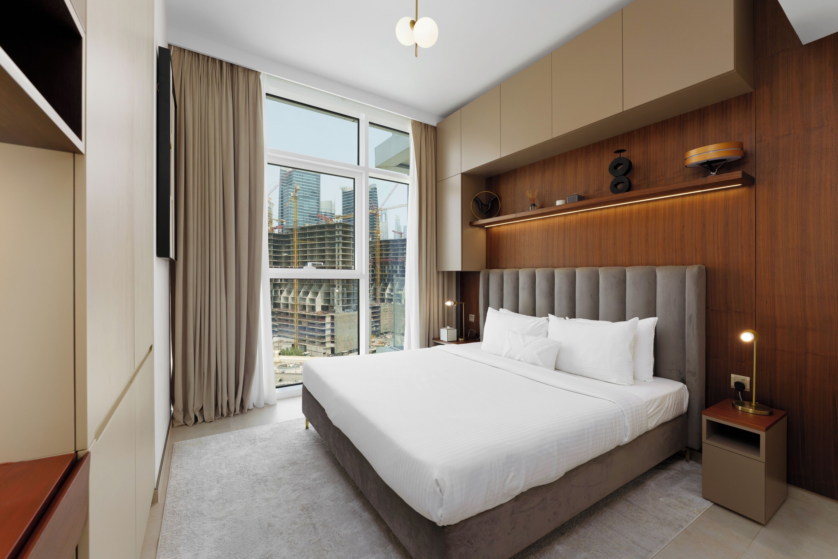 Una habitación de hotel moderna con una cama grande, armario empotrado y vistas a la ciudad.