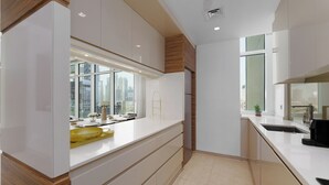 A modern kitchen with white cabinetry, a large window with a city view, and a built-in oven. - Maison Privee - Tranquil Apt w/ Mesmerizing Views cls to Marina (Dubai)