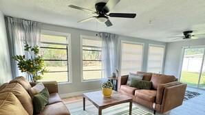 A spacious living room with two brown leather sofas, a wooden coffee table, and a striped rug. - Charming large 2-bedroom house 15 min to beach (Palm Coast)