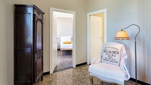 A hotel room with a bed, a wardrobe, a chair with a blanket, and a lamp. - Camogli Gulf View by Wonderful Italy (Camogli)