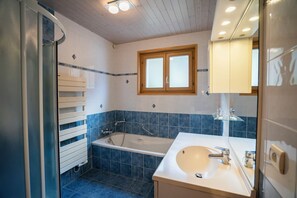 A bathroom with a bathtub, a sink, and a window with frosted glass. - Chalet 9 persons, near Linga gondola, with Wi-Fi - Chatel Reservation (Châtel)