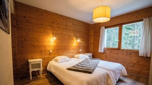 A wooden-paneled room with a bed, a bedside table, and a window with curtains. - Chalet 9 persons, near Linga gondola, with Wi-Fi - Chatel Reservation (Châtel)