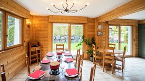 A wooden interior with a dining table set for four, a chandelier, and large windows. - Chalet 9 persons, near Linga gondola, with Wi-Fi - Chatel Reservation (Châtel)
