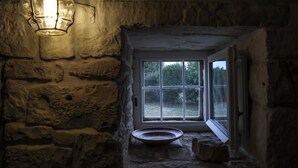 A stone-walled room with a window and a hanging light fixture. - Trulletto with swimming pool in Monopoli (Monopoli)