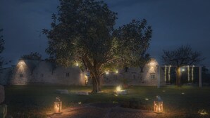 A stone building with a tree in front, surrounded by lanterns and string lights. - Trulletto with swimming pool in Monopoli (Monopoli)