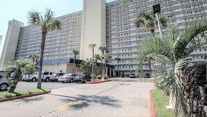 Un gran hotel con varios pisos, estacionamiento y palmeras.