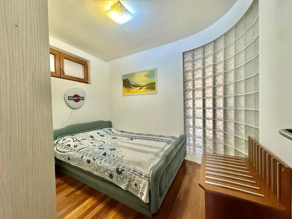 Une chambre à coucher avec un lit, un radiateur fixé au mur, une fenêtre à carreaux et un tableau.