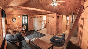 Interior acogedor de una cabaña con comedor, cocina y una escalera.