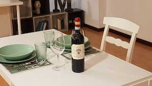 A dining table with a bottle of wine, glasses, and plates. - Casa Marzia: cosy, quiet, close to the centre and Sant'Orsola Malpighi Hospitals (Bologna)