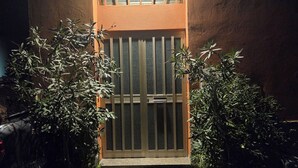 A building entrance with a metal gate, potted plants, and a light above the door. - Casa Marzia: cosy, quiet, close to the centre and Sant'Orsola Malpighi Hospitals (Bologna)