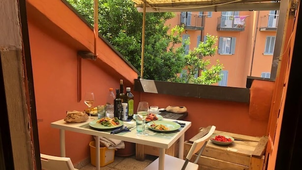 A small outdoor dining area with a table set for two, surrounded by orange walls and a view of a residential building. - Casa Marzia: cosy, quiet, close to the centre and Sant'Orsola Malpighi Hospitals (Bologna)