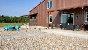 Een modern gebouw met een patio, voorzien van buitenmeubilair en een barbecue.