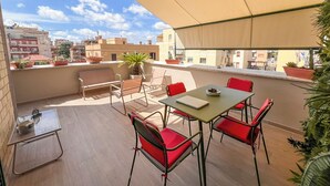 Une terrasse sur le toit avec une table et des chaises, un ordinateur portable et des plantes en pot.