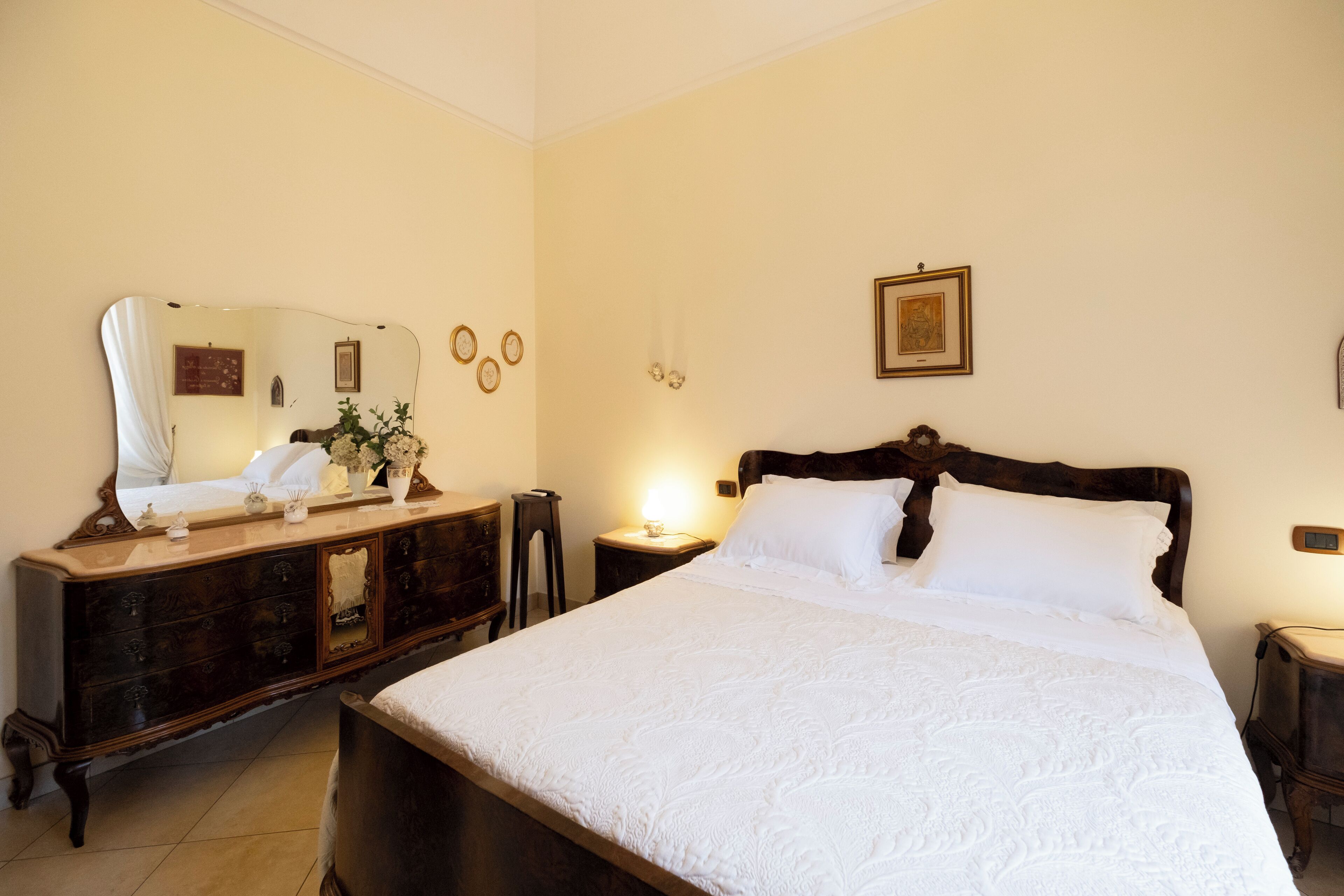 A bedroom with a large bed, a dresser, a mirror, and a nightstand.