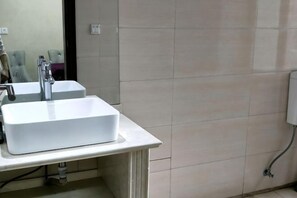 A bathroom with two white sinks, a mirror, and a tiled wall.