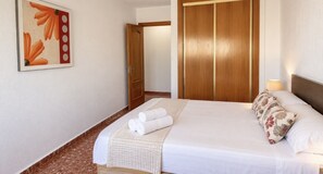 Een hotelkamer met een bed, een houten garderobe, een schilderij aan de muur en een badkamers deur.
