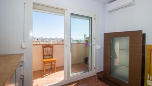 A balcony with a city view, a sliding glass door, a wooden chair, and a small table. - La Noria Floor 1 (Torre Del Mar)