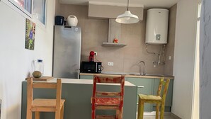 Una cocina con una isla central, microondas, hervidor y calentador de agua.