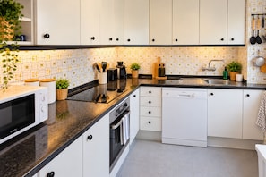 Une cuisine moderne avec des armoires blanches, un comptoir noir et un pare-feu décoré.
