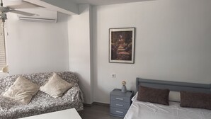 Ein Schlafzimmer mit Bett, Sofa, einem kleinen Tisch, einem Nachttisch und einem Deckenventilator.
