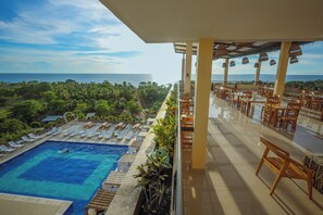 A poolside area with lounge chairs and a view of the ocean.