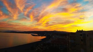 A sunset over a river with buildings along the shore. - Loft in 1st Line Residential with pool (Algarrobo Costa)