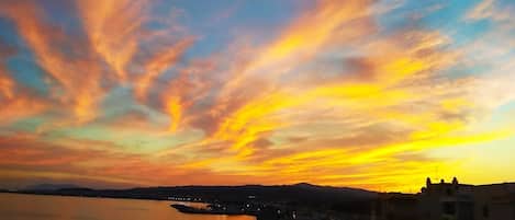A sunset over a river with buildings along the shore.