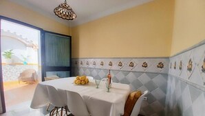 Comedor con una mesa preparada para cuatro, una botella de vino y un cuenco de limones.
