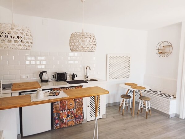 Una cocina moderna con armarios blancos, una isla de madera e iluminación colgante.