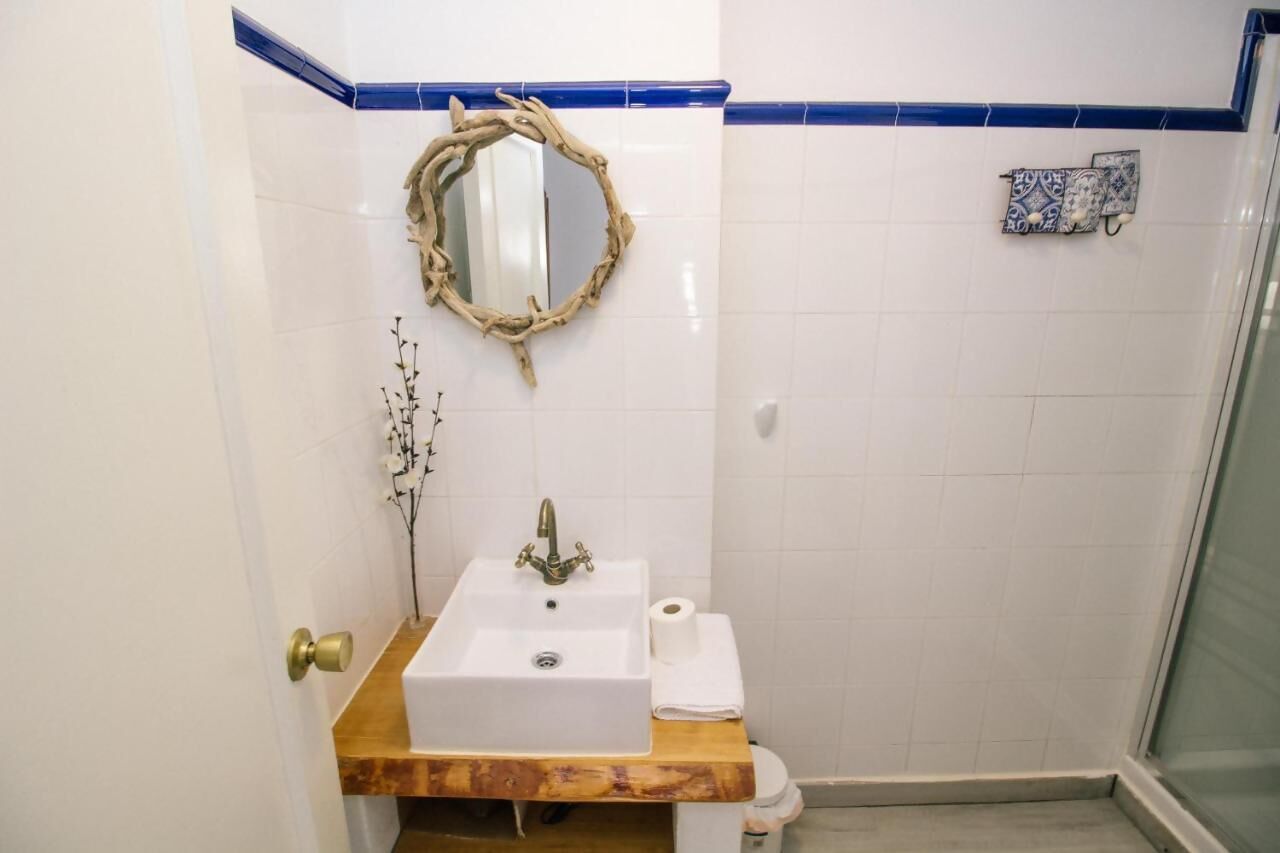 Ein Badezimmer mit weißem Waschbecken, einem Spiegel und einer Dusche.
