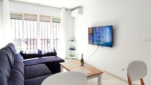 A modern living room with a sofa, a dining table, and a TV mounted on the wall. - FANTASTIC FULLY RENOVATED APARTMENT (Torre Del Mar)
