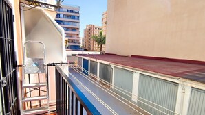 A balcony with a metal railing, a wooden floor, and a view of adjacent buildings. - FANTASTIC FULLY RENOVATED APARTMENT (Torre Del Mar)