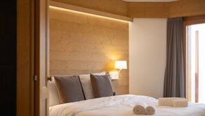 A hotel room with a wooden headboard, a bed with white linens, a bedside lamp, and a window with curtains. - Domaine des Reines C1 - Swimming pool (Haute-Nendaz)