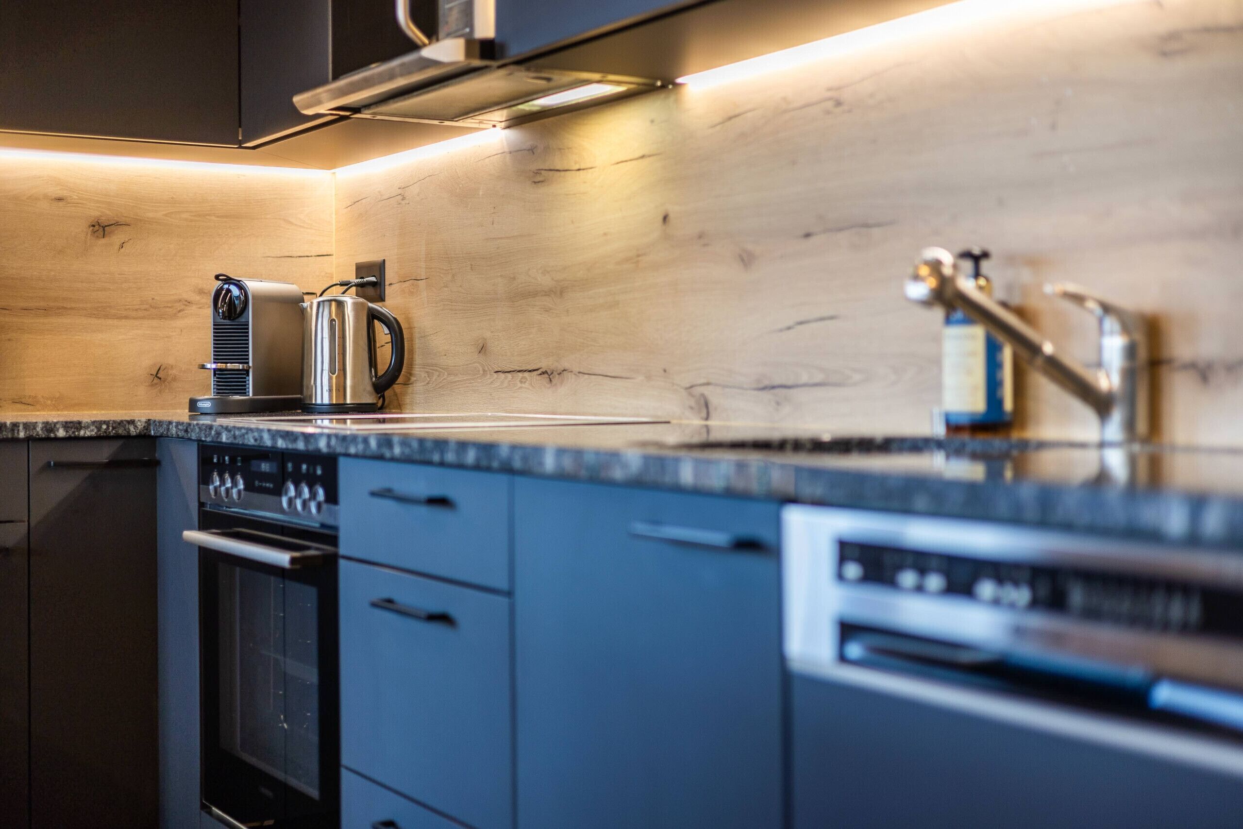 A modern kitchen with a built-in oven, a coffee maker, and a dishwasher.