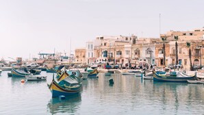 Un port où des bateaux sont amarrés, avec une rangée de bâtiments en arrière-plan.