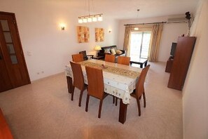 Uma sala de jantar com uma mesa retangular, seis cadeiras e um candelabro.