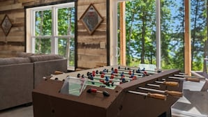 A foosball table in a room with wooden walls and large windows.