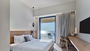 Une chambre d’hôtel moderne avec un grand lit, un bureau et une vue sur la mer.