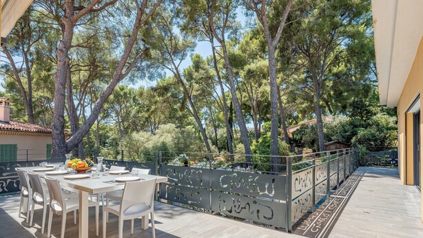 An outdoor dining area with a table set for four, surrounded by white chairs, and a decorative railing with graffiti. - Appartement Exceptionnel de 230m2 Mansardé vue mer (La Ciotat)