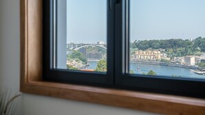 A window view of a cityscape with a bridge, buildings, and a river. - GuestReady - Stunning Douro River Vista (Vila Nova de Gaia)