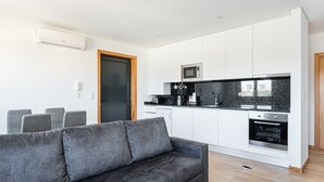 A modern kitchen with white cabinets, a black countertop, and stainless steel appliances. - GuestReady - Stunning Douro River Vista (Vila Nova de Gaia)
