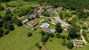 An aerial view of a rural village with houses, fields, and a swimming pool.