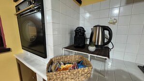 Een keuken met een fornuis, een koffiezetapparaat en een mand met tijdschriften op het aanrecht.