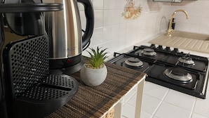 Een keuken met een koffiezetapparaat, een kleine potplant en een gasfornuis.