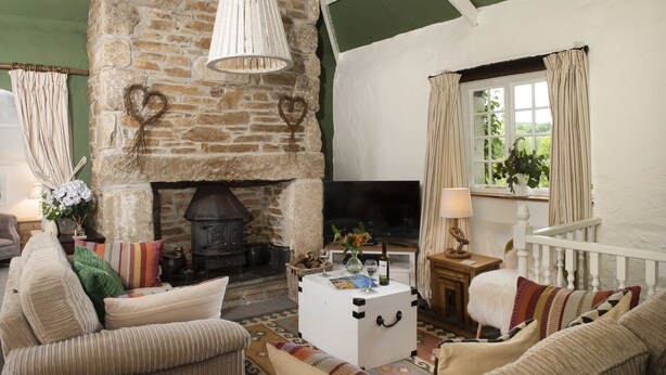Una sala de estar acogedora con chimenea de piedra, una mesa de centro blanca y asientos cómodos.