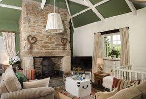A cozy living room with a stone fireplace, a white coffee table, and comfortable seating. - Tucked away in tranquil seclusion within the private Whitehay Estate, sits this charming country cot (Bodmin)