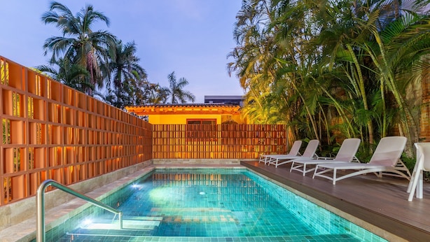 A swimming pool with tiled flooring, surrounded by a wooden fence and palm trees. - Chiapas boutique apartment (Bucerías)